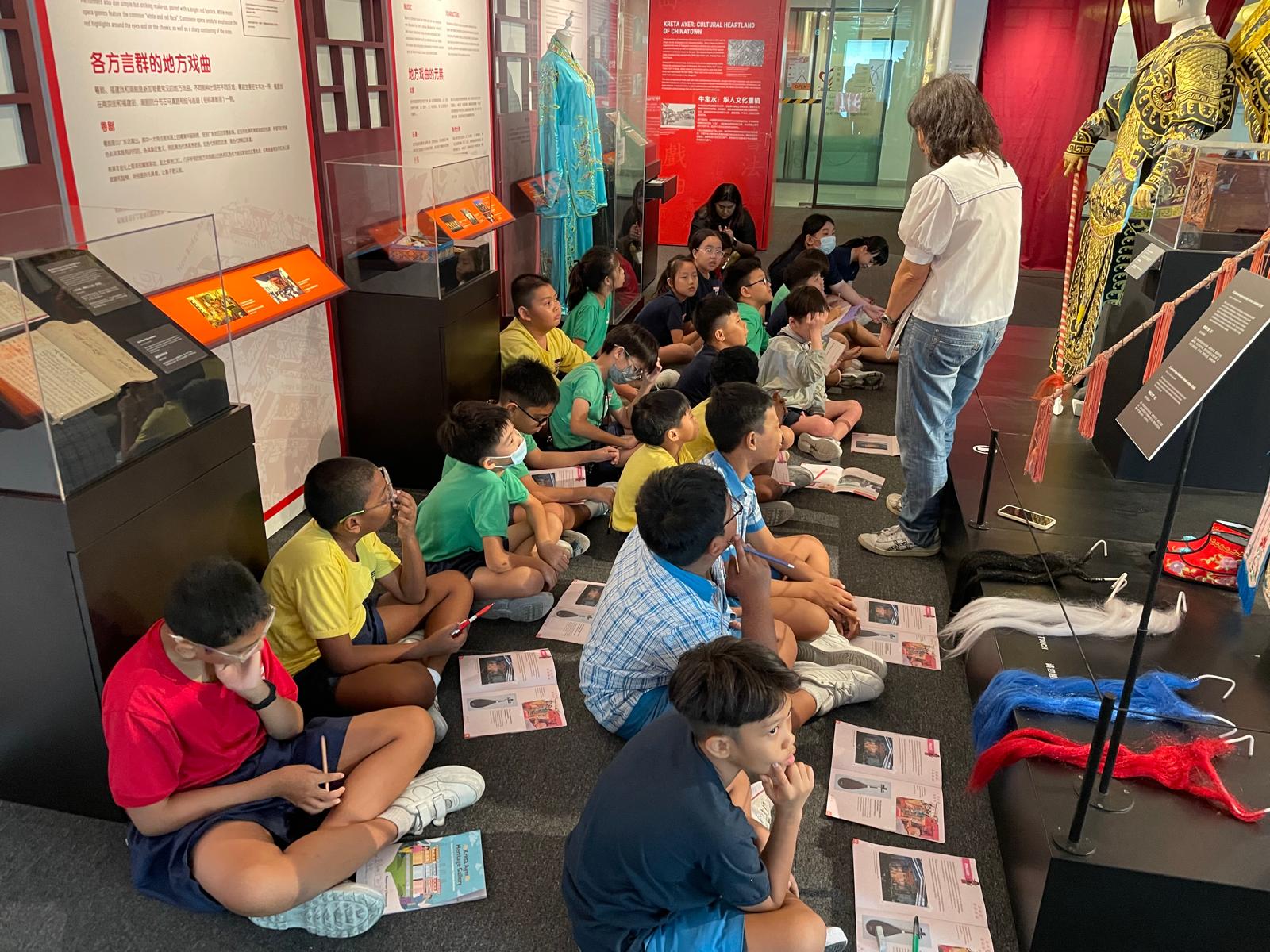 This image shows a group of P3 students listening to a talk about Chinese Opera.