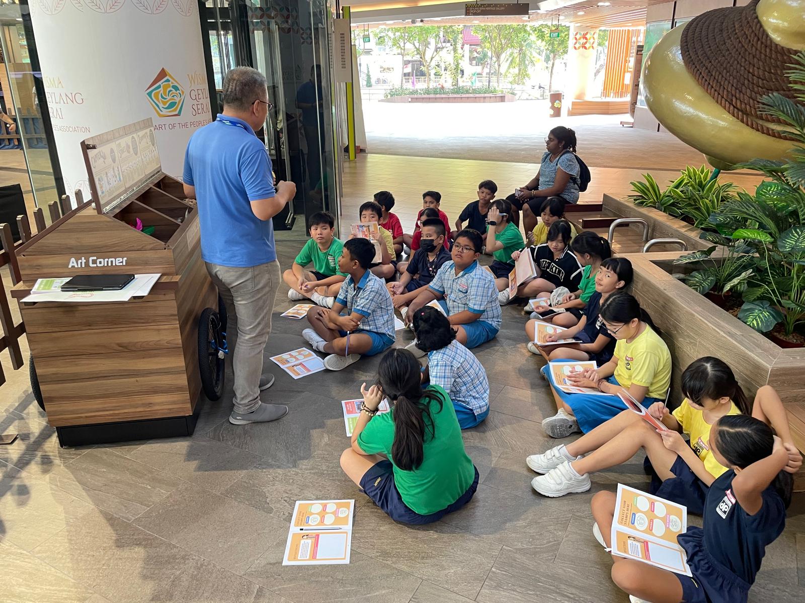 A group of pupils sitting on the floor listening to the staff at Geylang Serai.