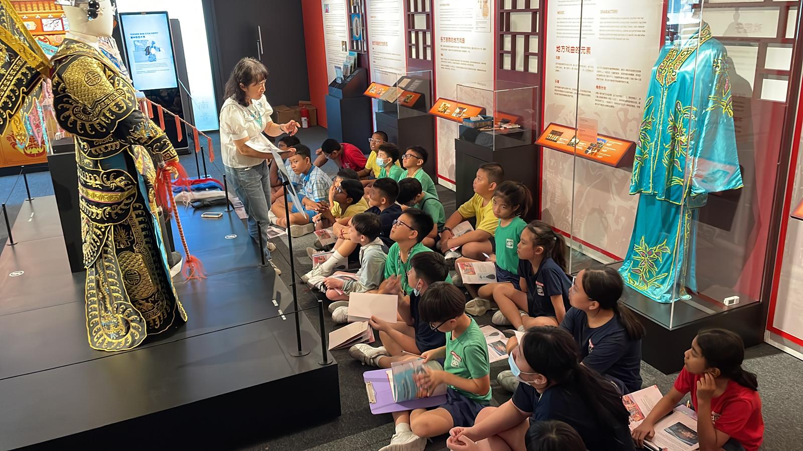 This image shows a group of P3 students sitting down to listen to a talk about Chinese Opera.
