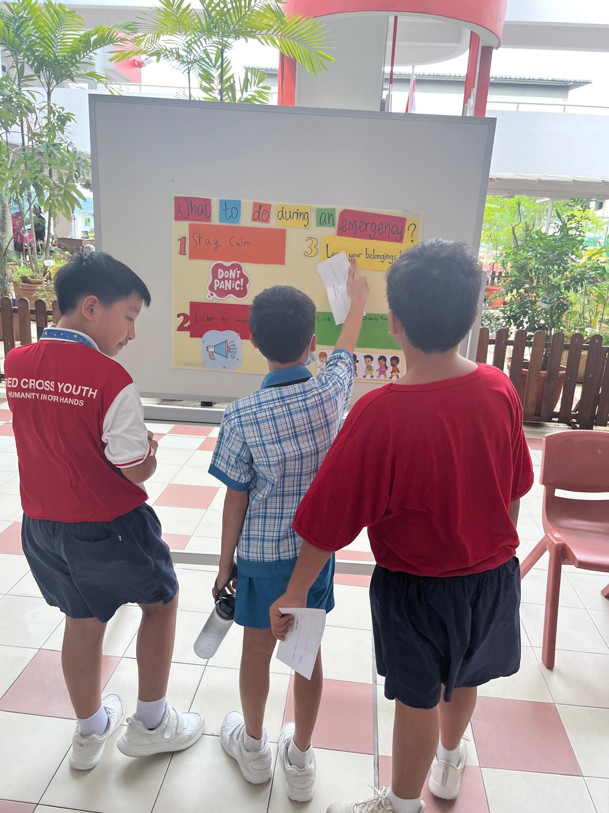 Some pupils looking at an inforgraphic  about Total Defence.